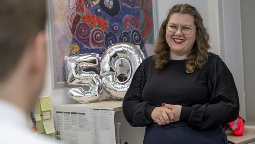 The picture shows Waleria Nichelmann in her office. There is a silver "50" in the centre of the picture. Nichelmann is smiling as she talks to the interviewer.